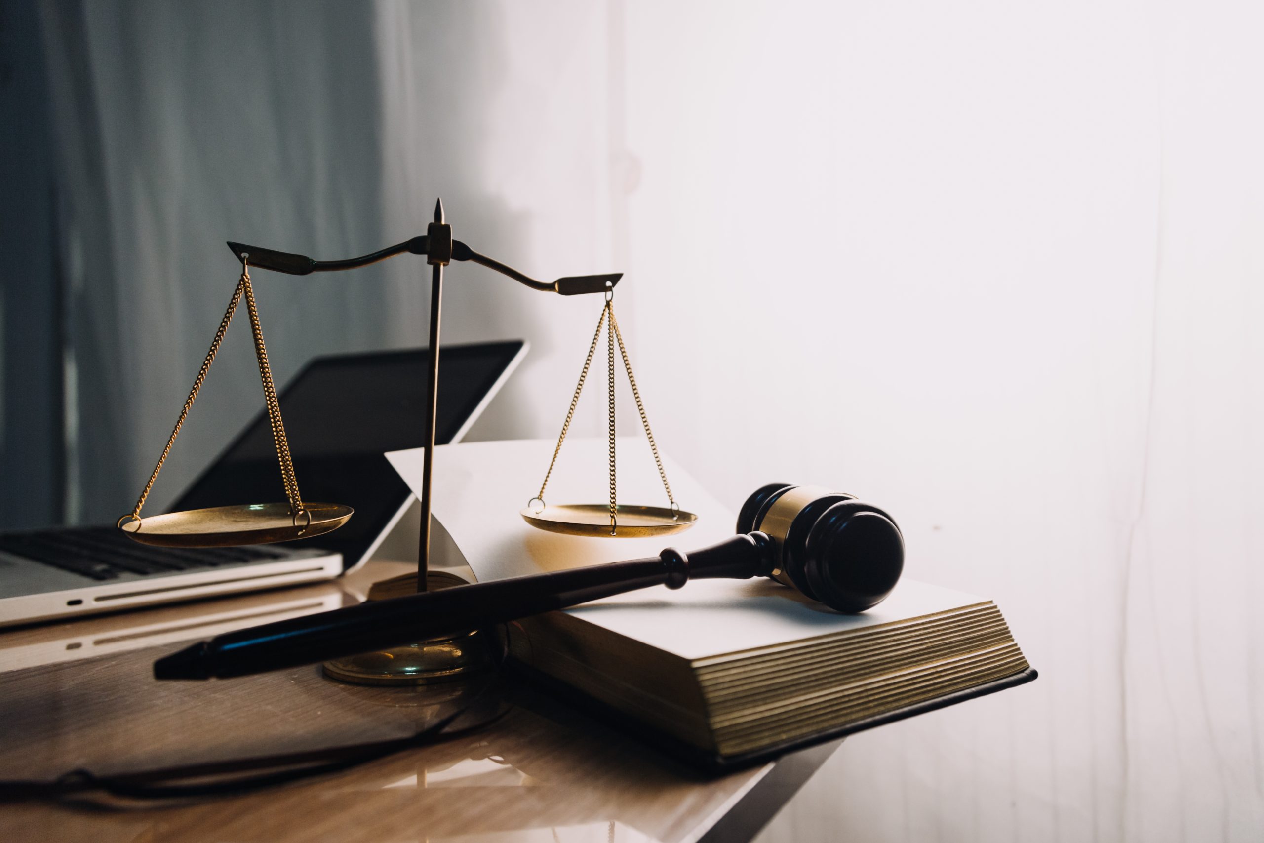 Justice and law concept.Male judge in a courtroom with the gavel, working with, computer and docking keyboard, eyeglasses, on table in morning light