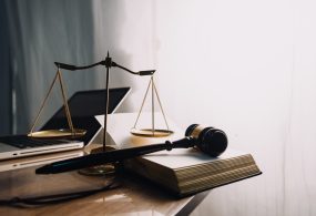 Justice and law concept.Male judge in a courtroom with the gavel, working with, computer and docking keyboard, eyeglasses, on table in morning light